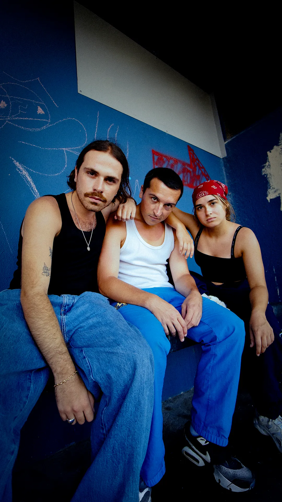 Trois personnes assises contre un mur bleu