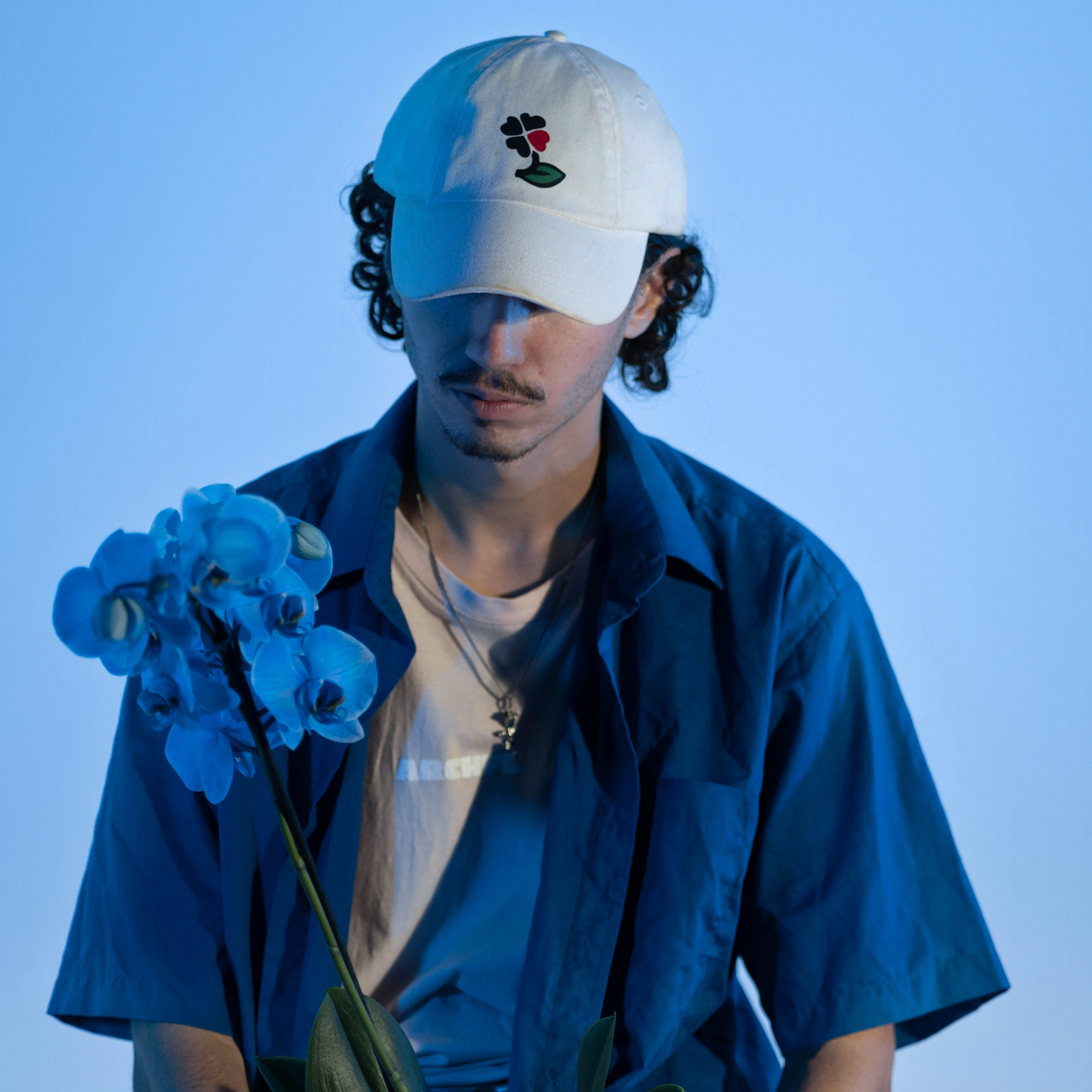 Portrait à la casquette et aux orchidées bleues