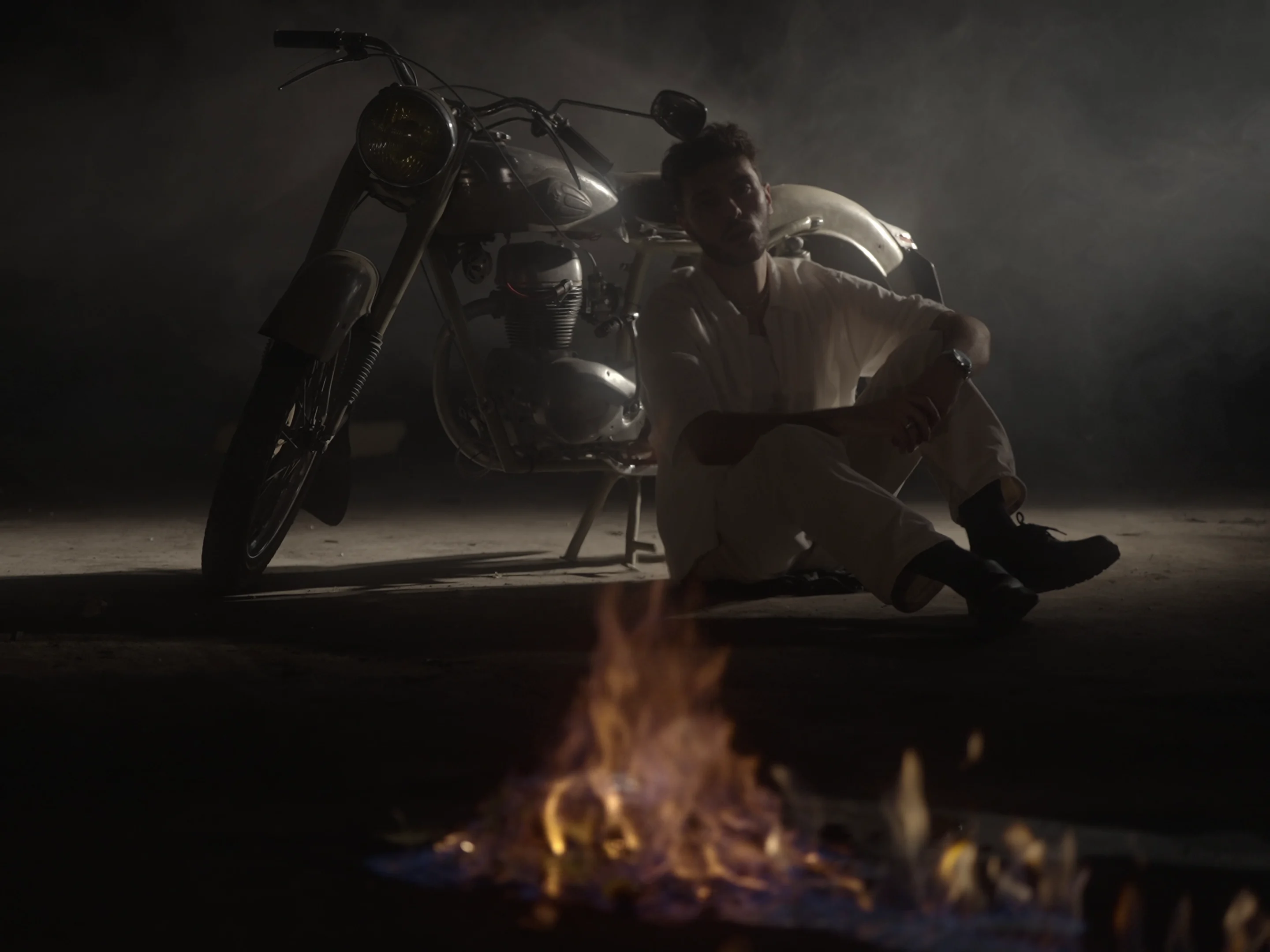 Lucas Paramour assis près d'une moto et d'un feu